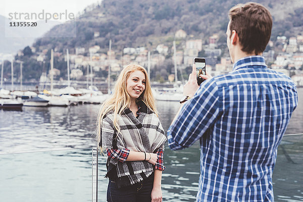 Junger Mann am Wasser fotografiert seine Freundin  Comer See  Italien
