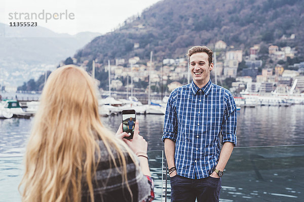 Junge Frau am Wasser fotografiert ihren Freund  Comer See  Italien