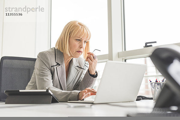 Reife Geschäftsfrau liest Update auf Office-Laptop