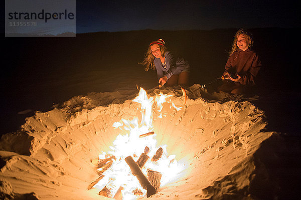 Zwei junge Mädchen kochen Essen am Lagerfeuer