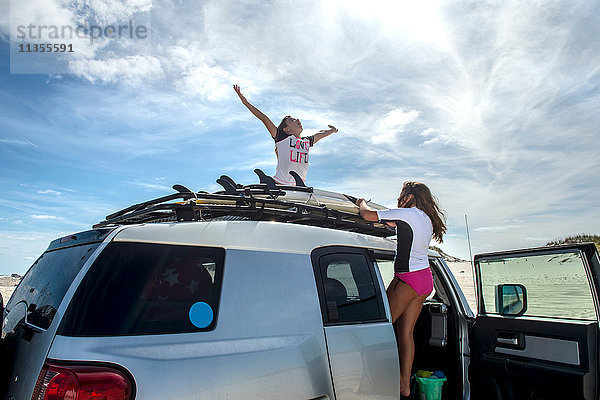 Zwei junge Mädchen binden Surfbretter vom Autodach ab