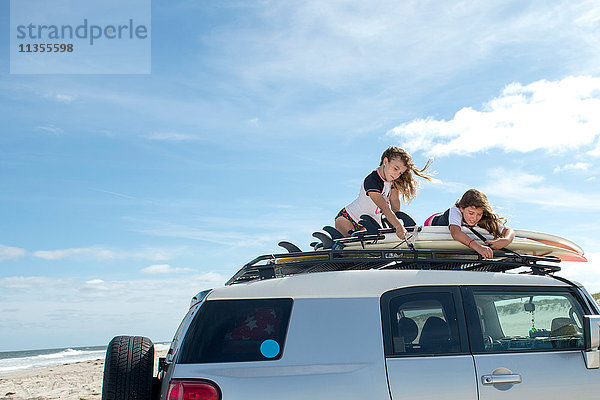 Zwei junge Mädchen sichern Surfbretter auf dem Autodach