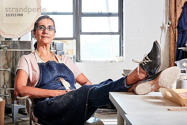 Frau sitzt mit erhobenen Füßen in Töpferwerkstatt