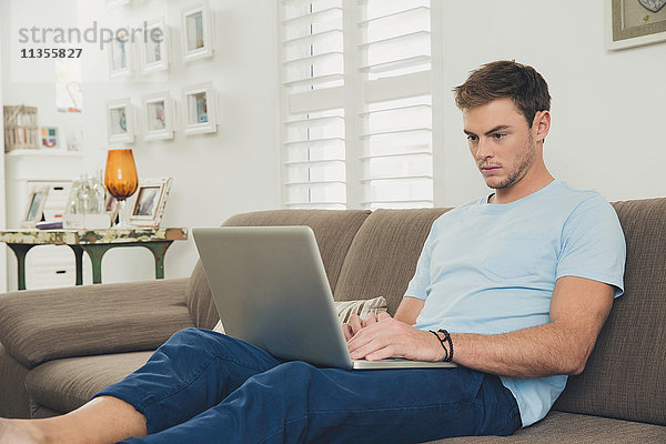 Mann auf Sofa mit Laptop