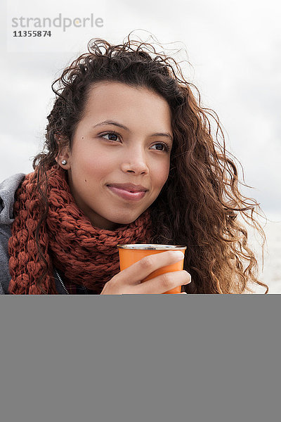 Junge Frau hält Tasse Kaffee an einem kalten Tag