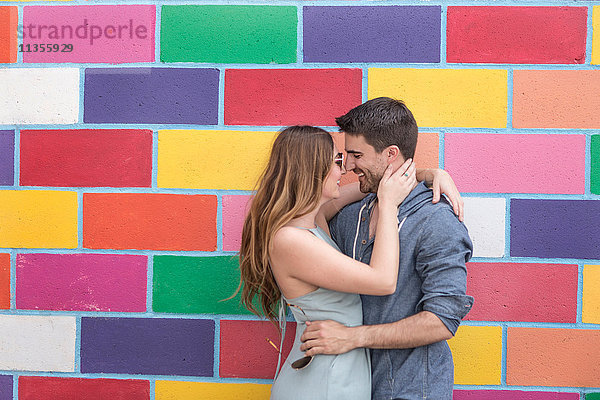 Paar vor bunt gekachelter Wand beim Umarmen  Coney Island  Brooklyn  New York  USA