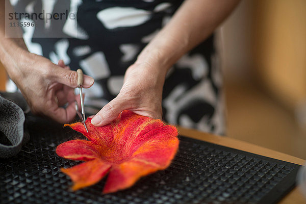 Frau schneidet und formt Filzblume