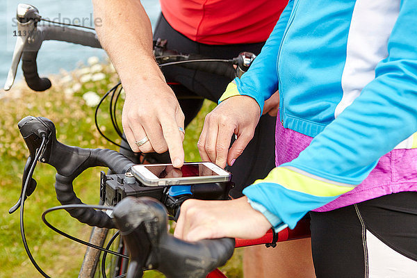 Radfahrer halten an  um GPS auf Mobiltelefonen zu benutzen