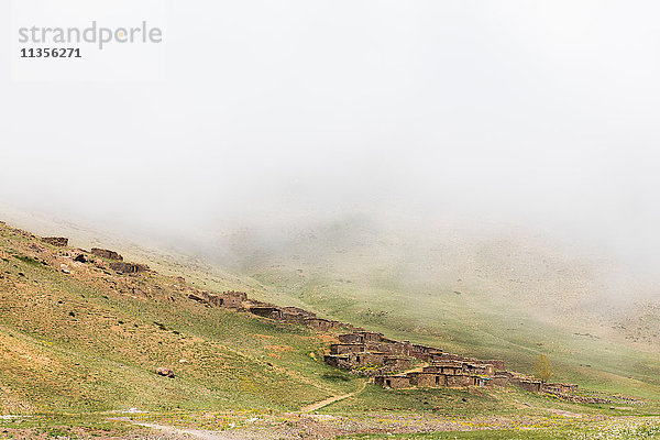 Nebliger Landschaftsblick auf Steinhäuser am Hang  Skigebiet Oukaimeden  Marrakesch  Marokko