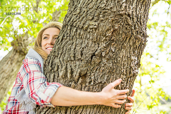 Frau umarmt lächelnden Baum