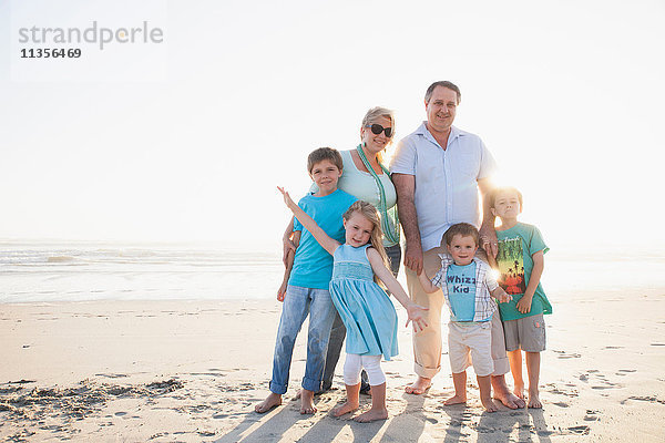 Familie am Strand schaut lächelnd in die Kamera