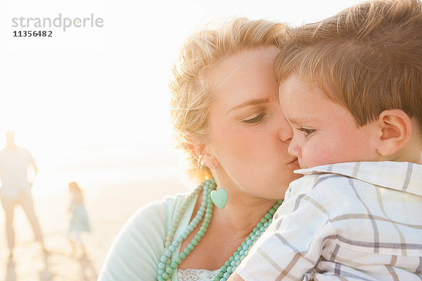 Mutter am Strand küsst Sohn auf die Wange