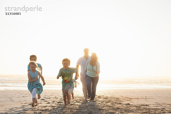 Frontansicht einer am Strand laufenden Familie