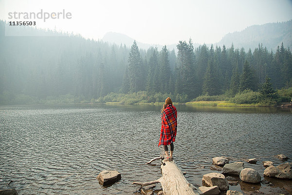 Frau eingehüllt in Schottenkaro-Decke mit Blick auf nebligen See  Mount Hood National Forest  Oregon  USA