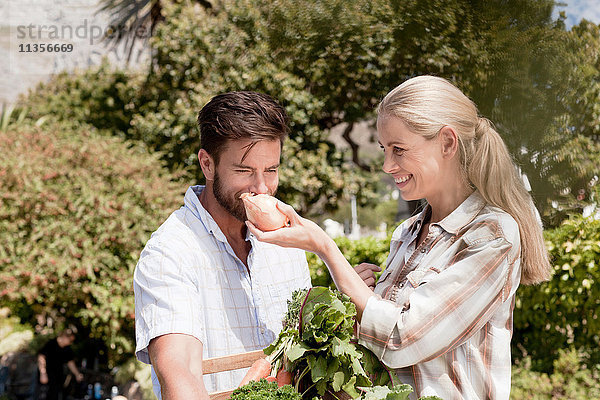 Reifes Paar im Garten  Frau hält frische Zwiebel für den Mann zum Riechen hoch