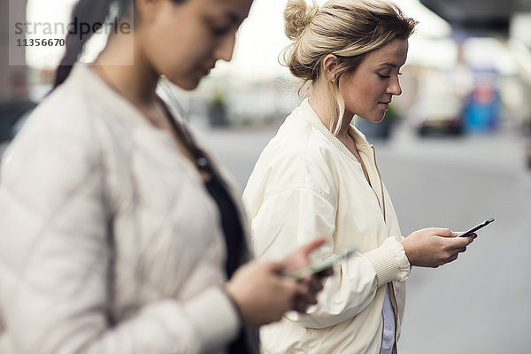 Seitenansicht von jungen Frauen mit Mobiltelefonen in der Stadt