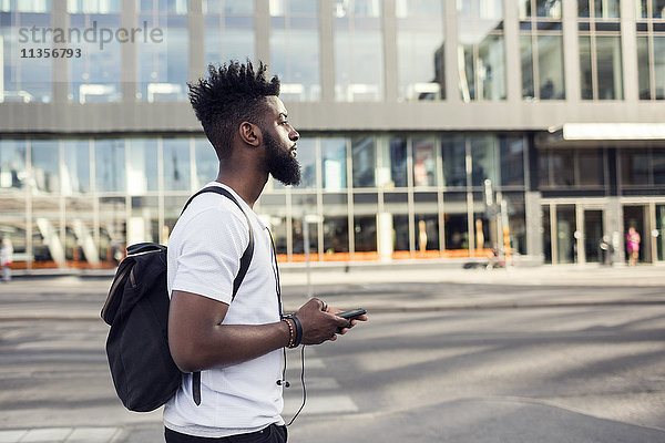 Seitenansicht des jungen Mannes mit Smartphone in der Stadt