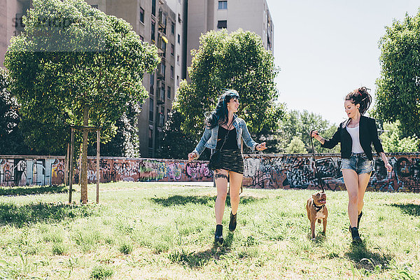 Zwei junge Frauen mit Pitbull-Terrier im Stadtpark