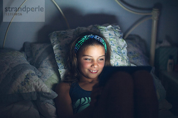 Mädchen im Bett mit digitalem Tablet lächeln
