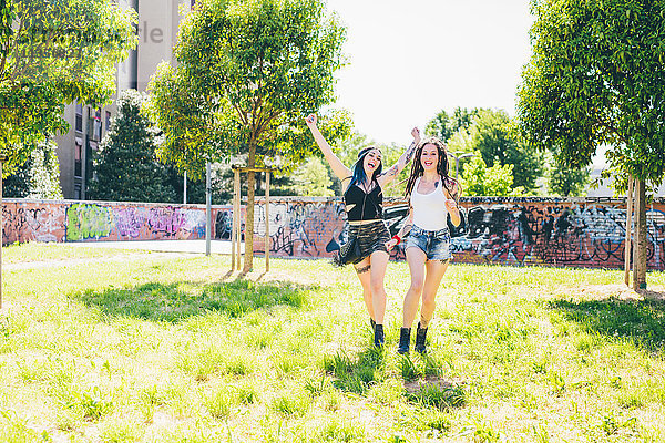 Zwei junge Frauen lachend und rennend im Stadtpark