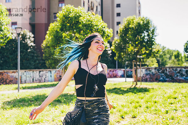 Junge Frau lachend und rennend im Stadtpark