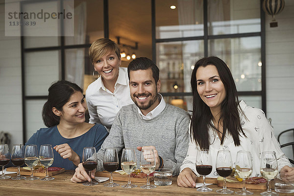 Portrait von lächelnden Geschäftsleuten bei der Weinprobe am Tisch