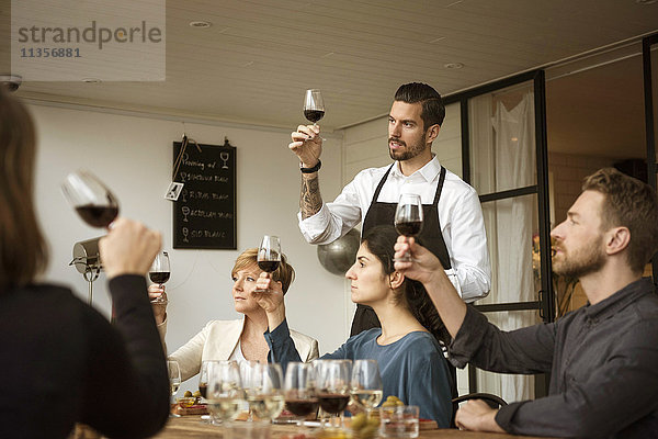 Der Mensch steht den Menschen bei und analysiert das Weinglas am Tisch.