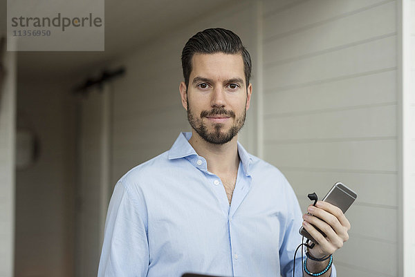 Porträt eines Geschäftsmannes mit Smartphone im Büro