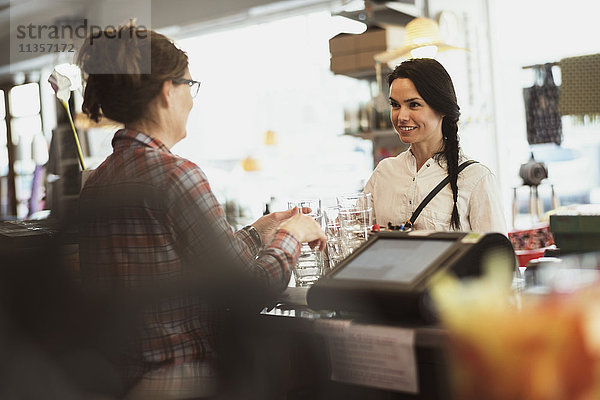 Besitzer zeigt dem Kunden Trinkgläser an der Kasse im Geschäft