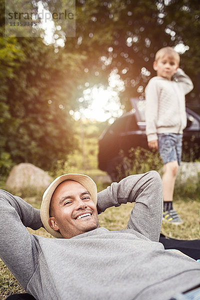 Porträt eines glücklichen Mannes  der mit einem Jungen im Hintergrund im Park steht.