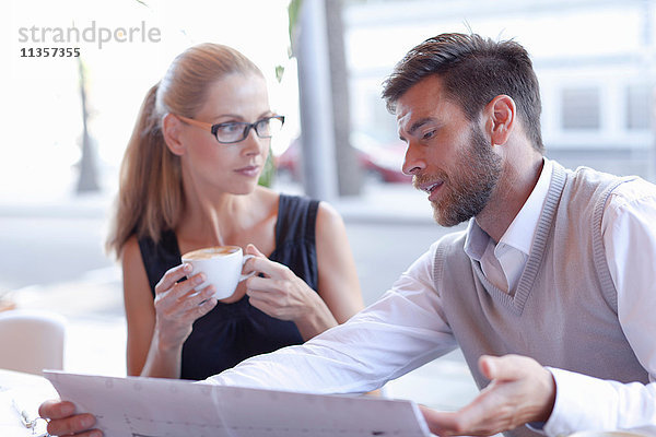 Reifer Mann und Frau  sitzen vor einem Café und diskutieren