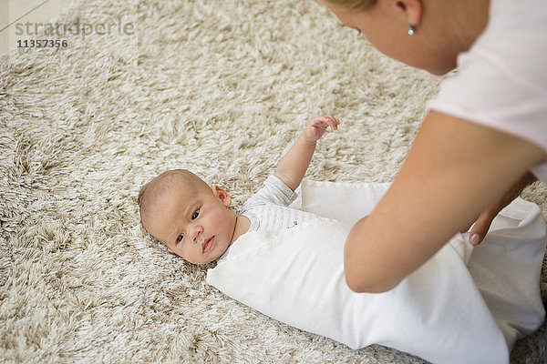 Wickeln Schritt 4. Mutter wickelt Baby Junge mit Decke