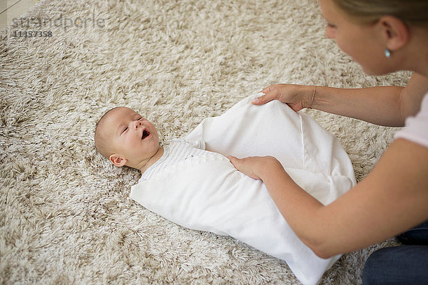 Einwickeln Schritt 5. Mutter wickelt den kleinen Jungen ein und deckt ihn mit einer Decke zu