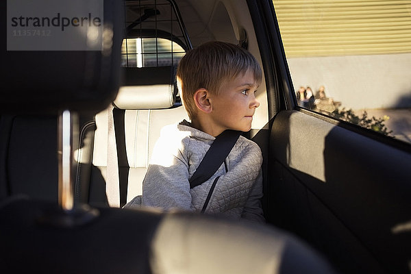 Junge sitzt im Elektroauto und schaut durchs Fenster.