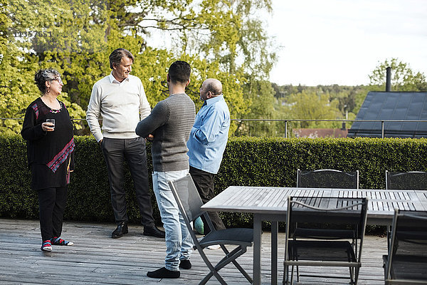 Multi-ethnische Freunde beim Reden am Tisch im Hof