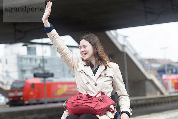 Junge Frau im Rollstuhl winkt vom Stadtbahnhof