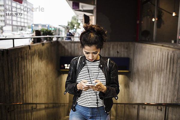 Frau mit Smartphone beim Gehen an der U-Bahn-Station