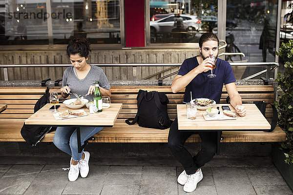 Volle Länge von Mann und Frau beim Mittagessen im Straßencafé