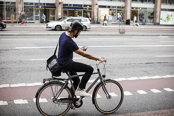 Volle Länge des Mannes beim Radfahren auf der Stadtstraße