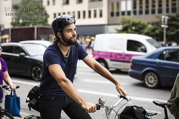Nachdenklicher Mann beim Radfahren im Verkehr auf der Stadtstraße