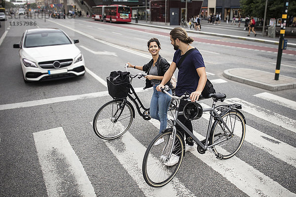 Lächelnde Freunde mit Fahrrädern über die Stadtstraße