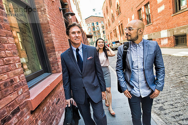 Geschäftsmänner und -frauen gehen lächelnd zusammen auf der Straße