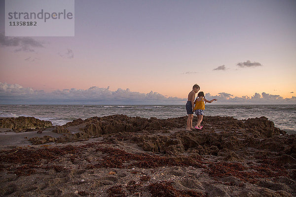 Mädchen und Bruder treten bei Sonnenaufgang über Strandfelsen  Blowing Rocks Preserve  Jupiter Island  Florida  USA
