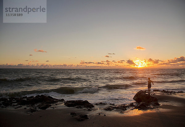 Junge schaut bei Sonnenaufgang aufs Meer hinaus  Blowing Rocks Preserve  Jupiter Island  Florida  USA
