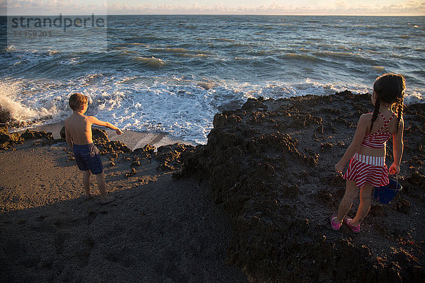 Junge und Schwester zeigen vom Strand auf Meereswellen  Blowing Rocks Preserve  Jupiter Island  Florida  USA