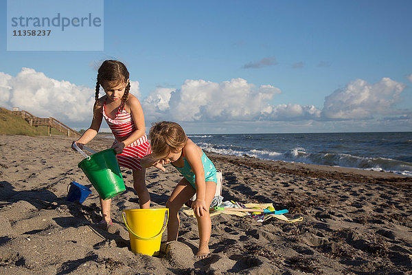 Zwei Schwestern spielen mit Spielzeugkübeln am Strand  Blowing Rocks Preserve  Jupiter Island  Florida  USA