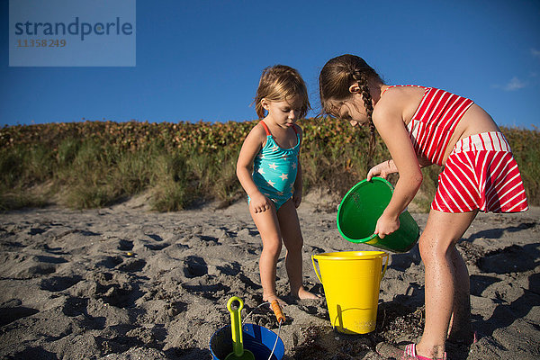 Mädchen und Schwester spielen mit Spielzeugeimern am Strand  Blowing Rocks Preserve  Jupiter Island  Florida  USA