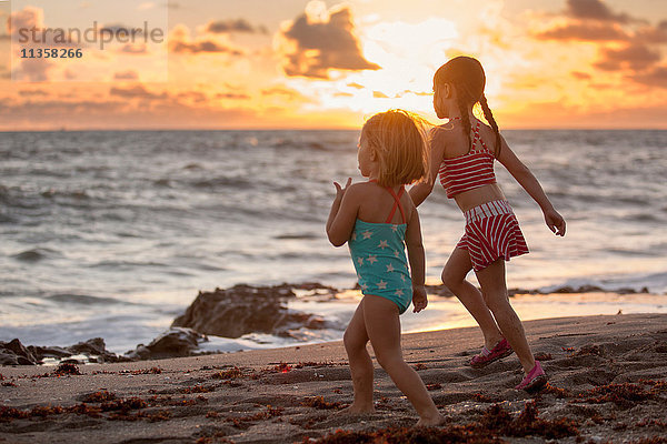 Mädchen und Schwester laufen bei Sonnenaufgang am Strand  Blowing Rocks Preserve  Jupiter Island  Florida  USA