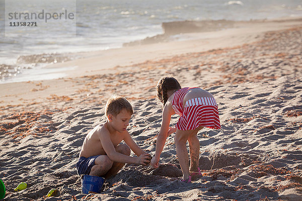 Junge und Schwester spielen mit Sand am Strand  Blowing Rocks Preserve  Jupiter Island  Florida  USA