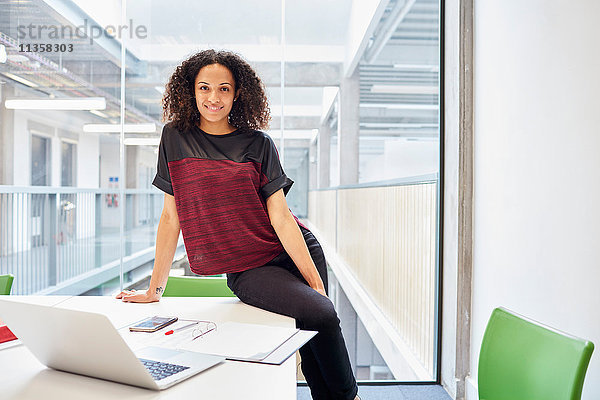 Porträt einer jungen Designerin  die im Designstudio am Schreibtisch sitzt